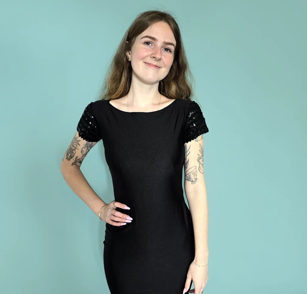 young woman wearing fitted dress with black sequins on sleeves 