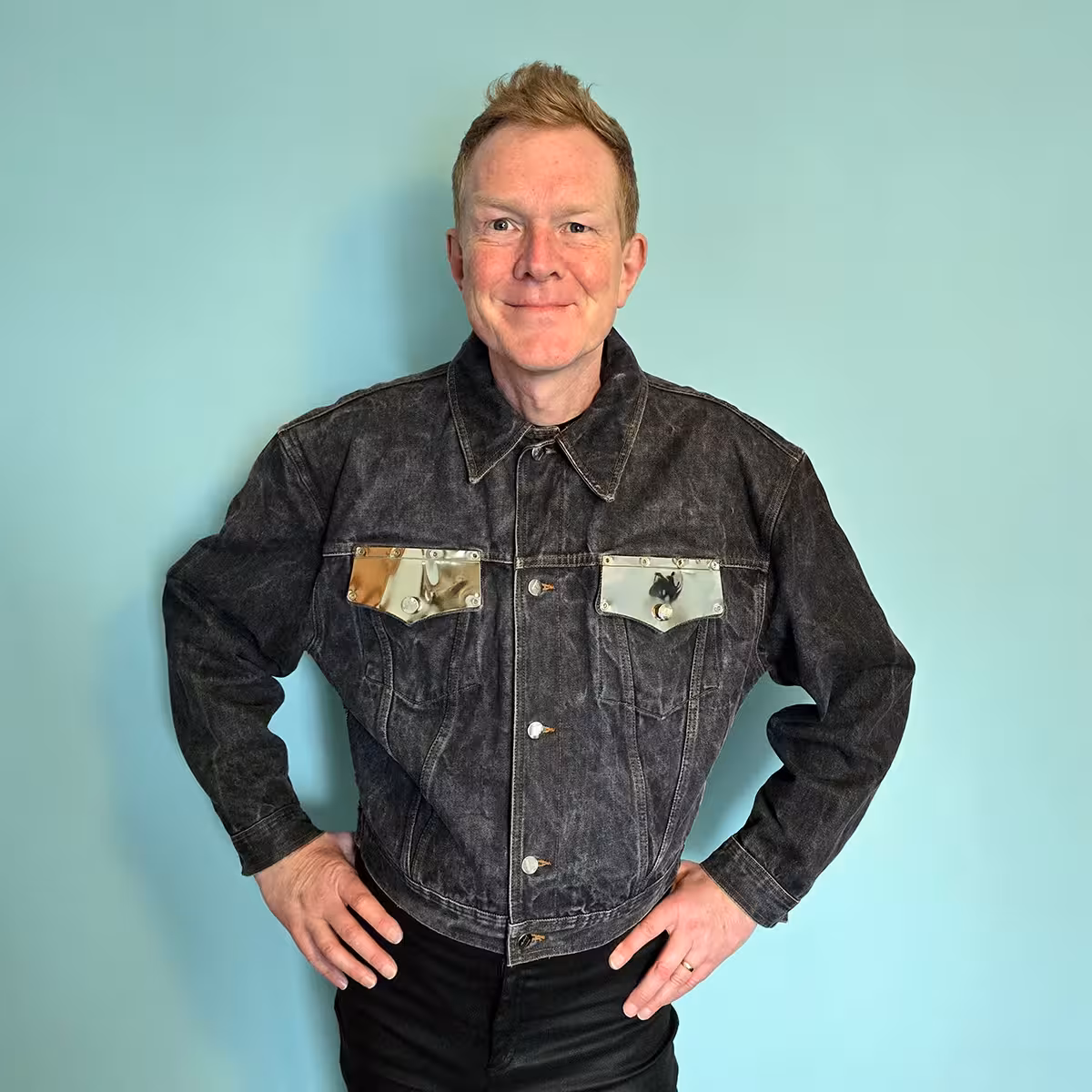 A person wearing a denim trucker jacket with steel plated pocket flaps