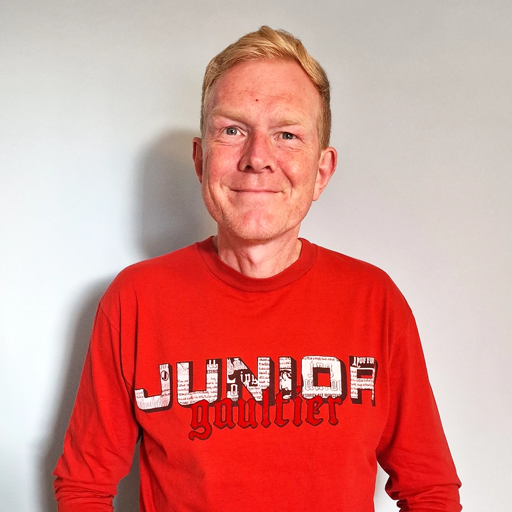 Person wearing red t-shirt with "Junior Gaultier" written on it.
