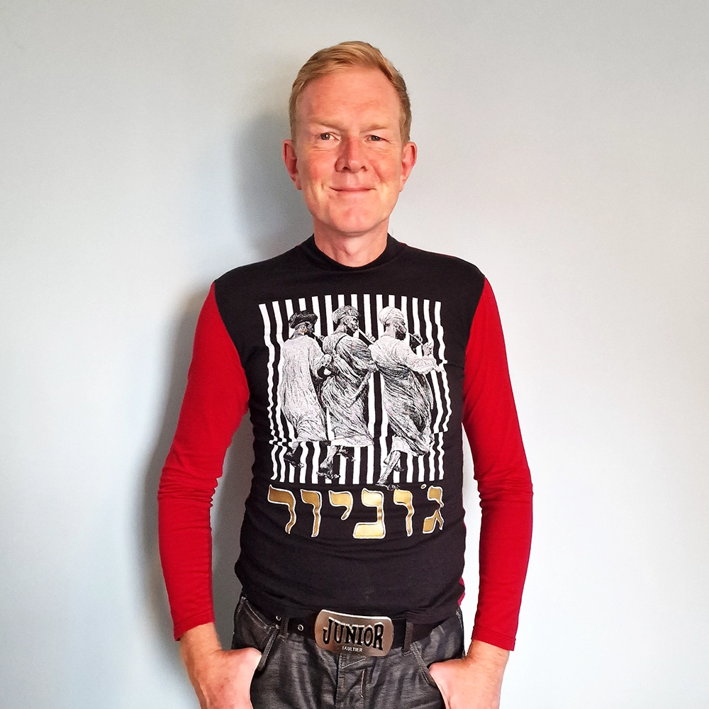 Person wearing a red and black T-shirt with an engraving of three pipers on the front.