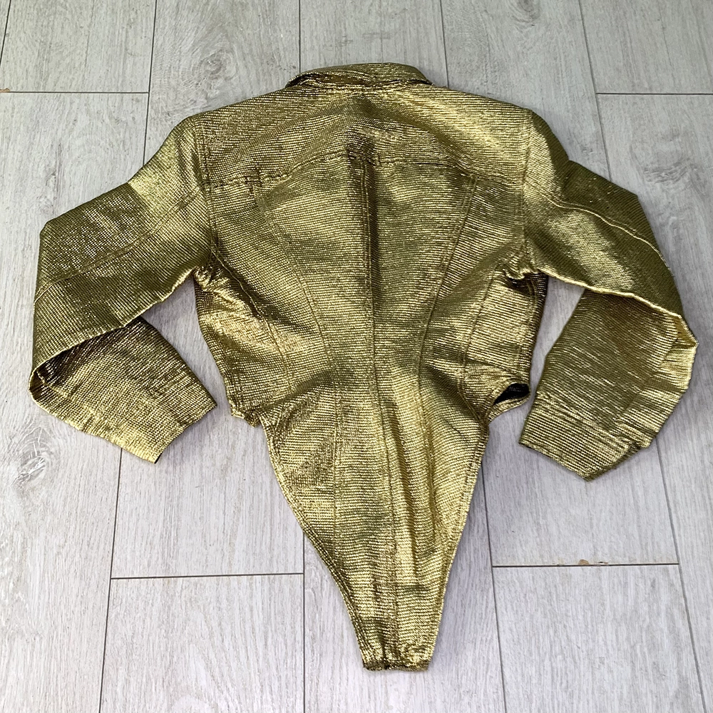 The back of a gold lame bodysuit on top of light wooden floorboards.