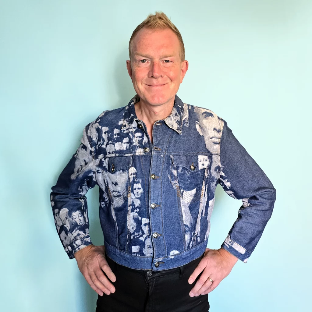 Man wearing denim jacket with pattern made up of random faces.