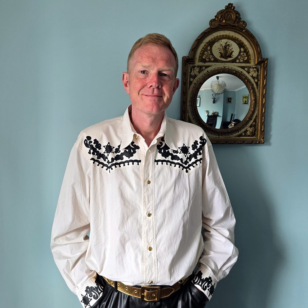 Man wearing a white shirt with western pattern.