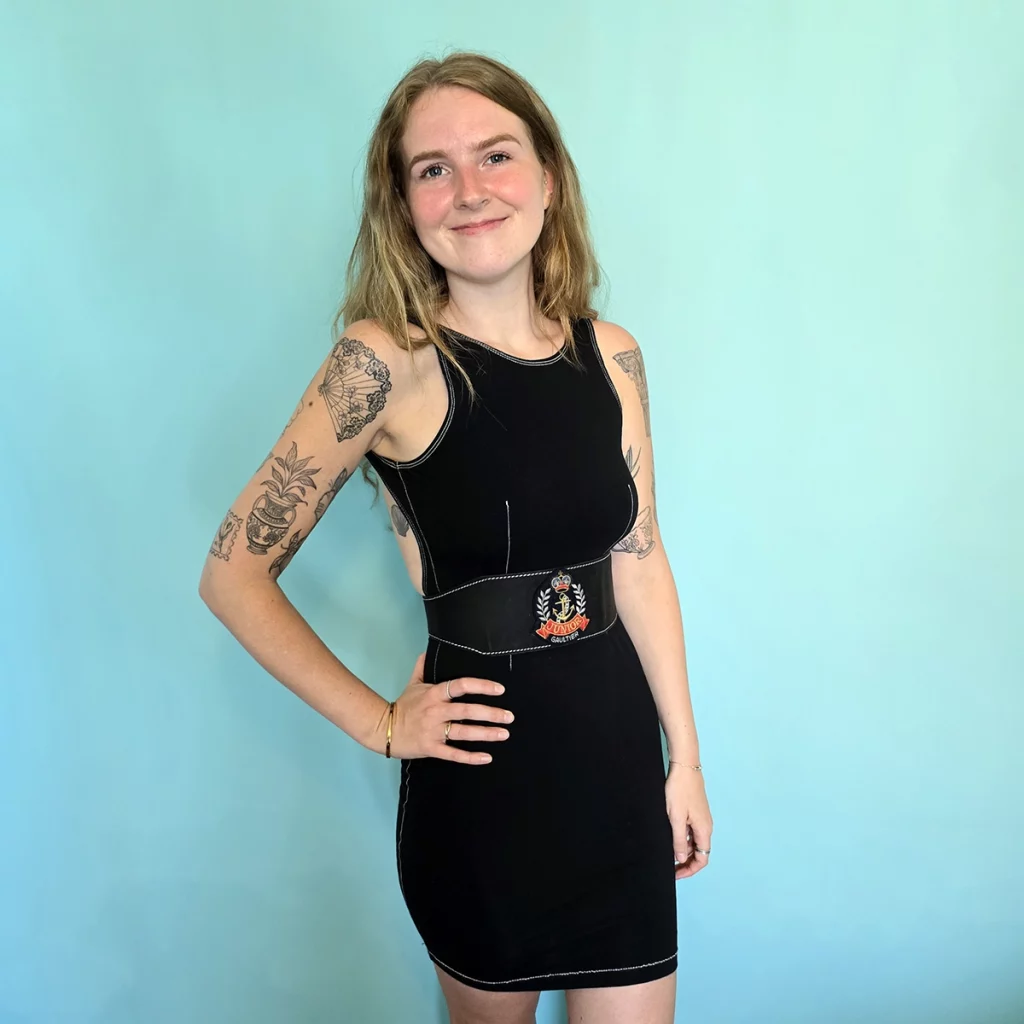 Woman wearing black dress with belt featuring an anchor and crown
