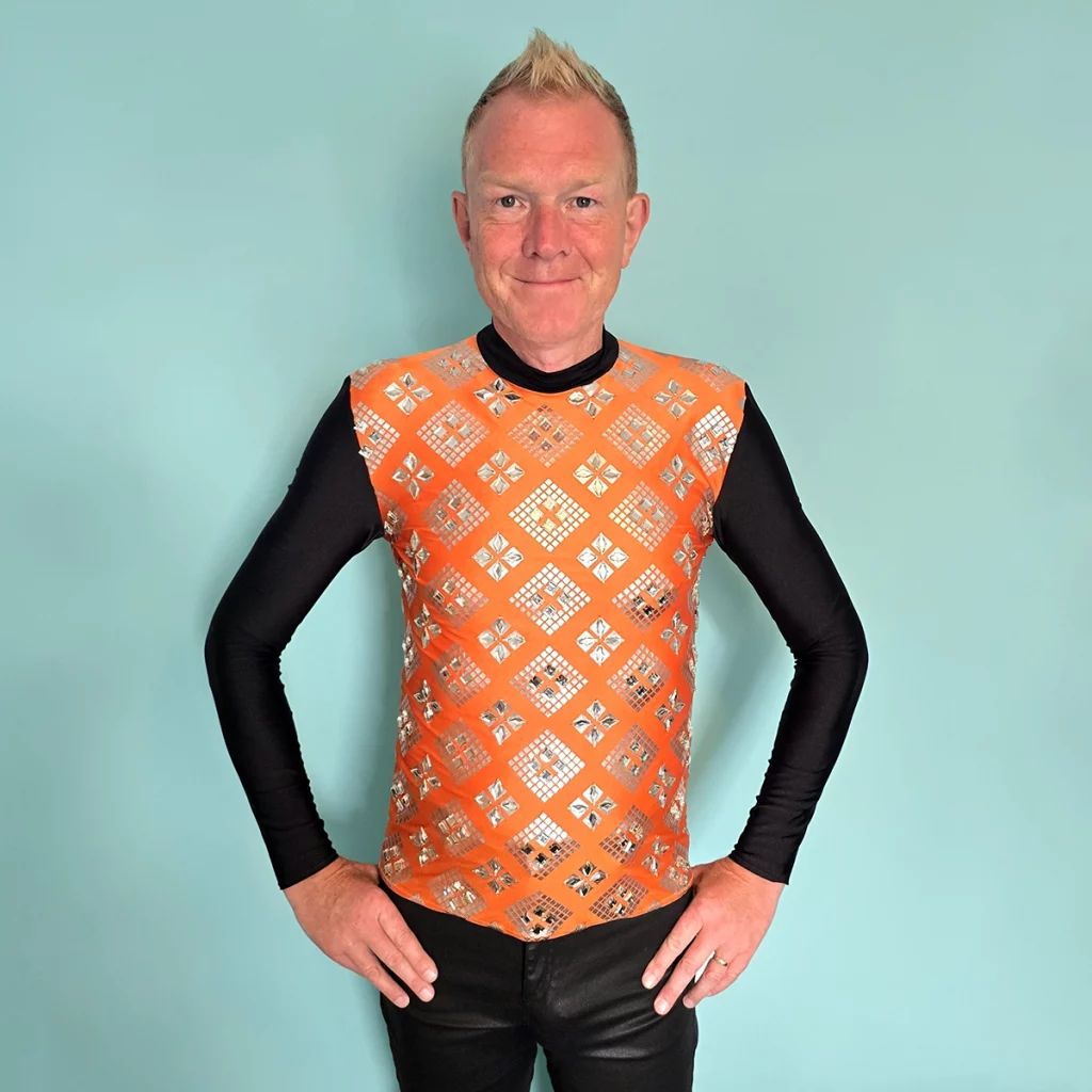 Person wearing an orange lycra top decorated with clear gemstones
