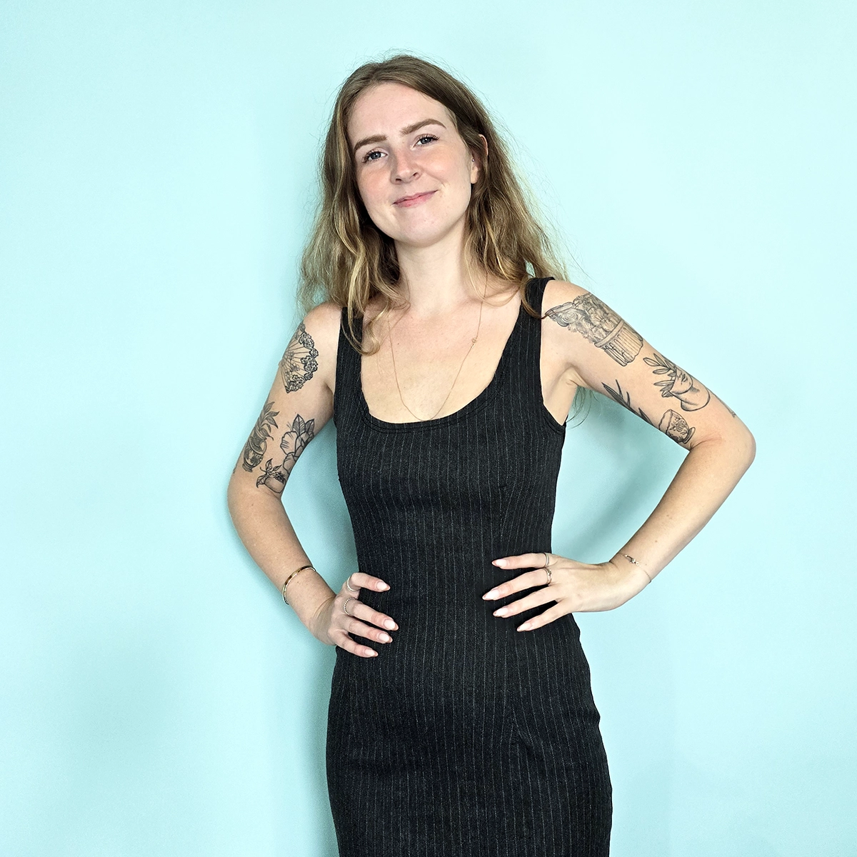 Lady with tattoos wearing a pinstripe dress