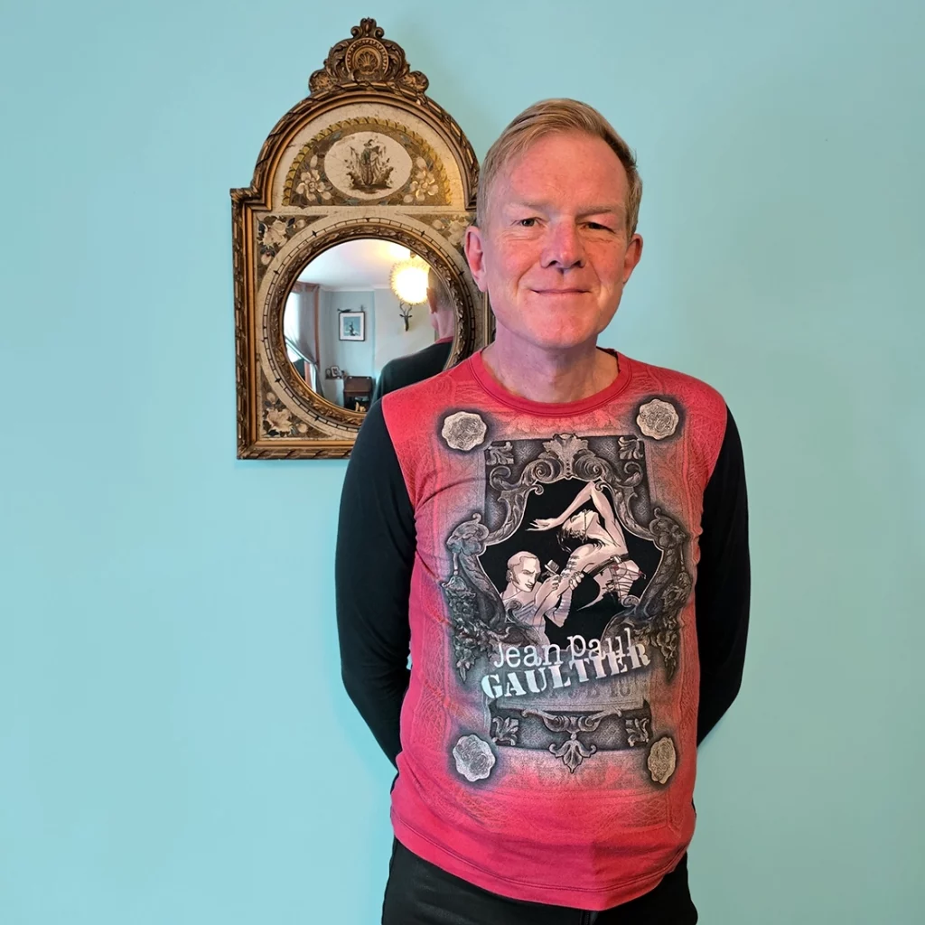 Man wearing top with an illustration of Jean Paul Gaultier tattooing a woman 